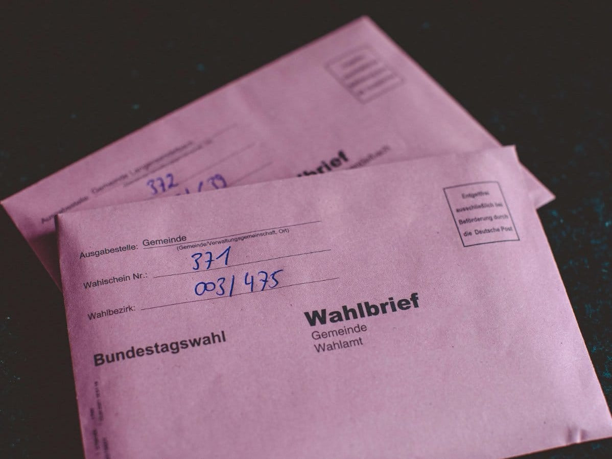 A distribution centre workbench with digital calipers, postage rate charts, and envelope types paired with correct stamp denominations.